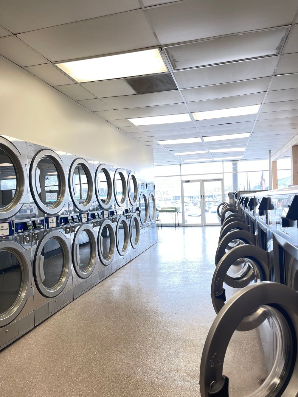 Aisle at Loveland Laundromat with rows of new stainless steel dryers and washers
